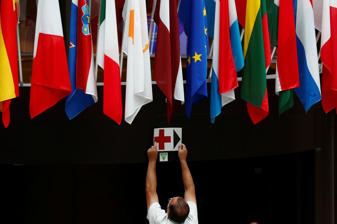 An EU Council employee places a sign near European Union national flags ahead of the EU leaders summit amid the coronavirus pandemic in Brussels, on July 16, 2020. Photo: Reuters 