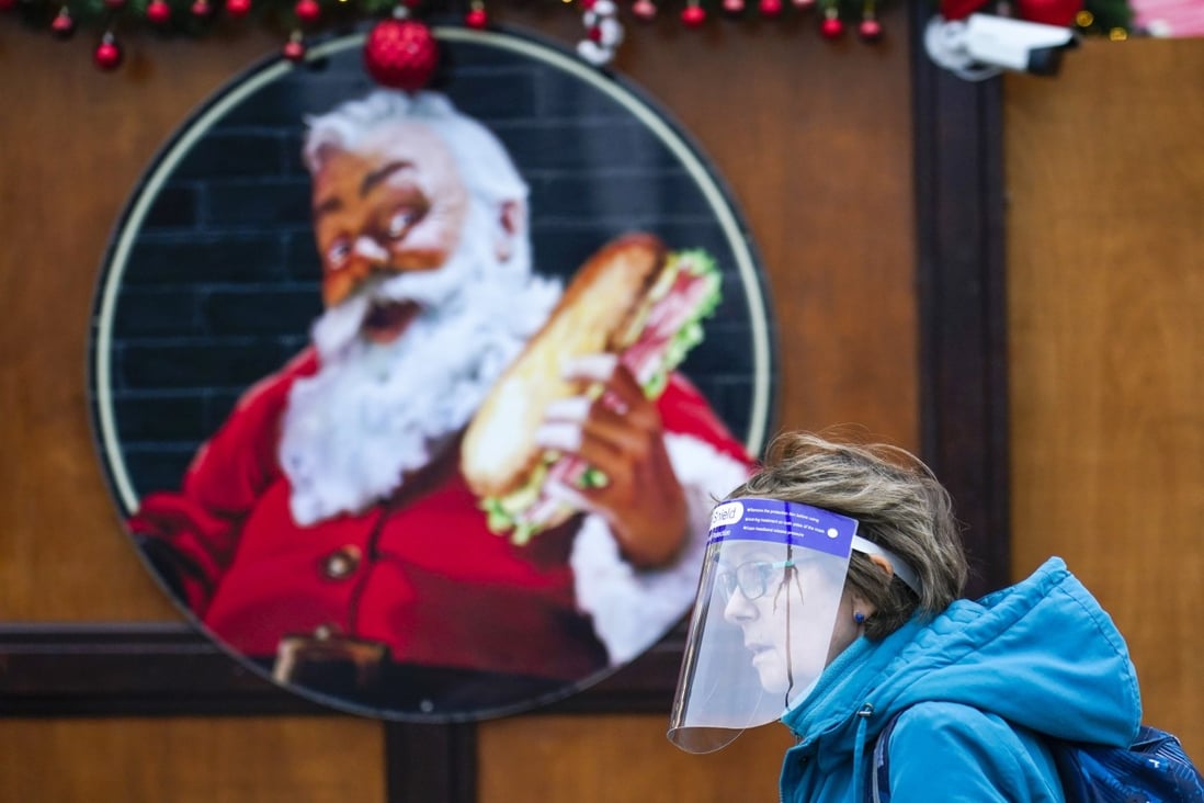 A woman wears a face shield as she walks past an image of Santa Claus at a Christmas market in London on Thursday. Photo: AP
