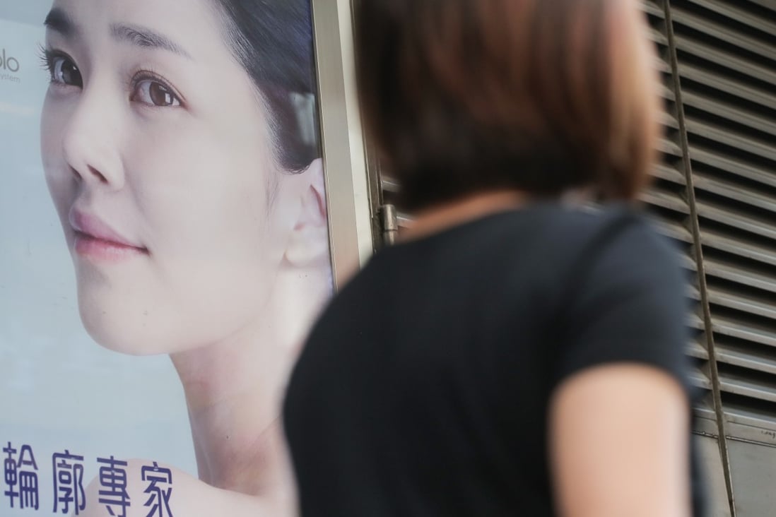 Pedestrians walk past an advertisement for a beauty centre in Causeway Bay. Photo: Paul Yeung