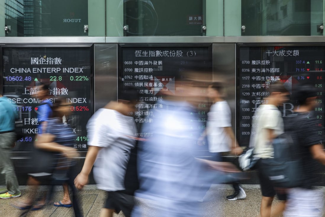 People walking past electronic boards showing recent stock market information in Mong Kok, Hong Kong. Photo: Sam Tsang