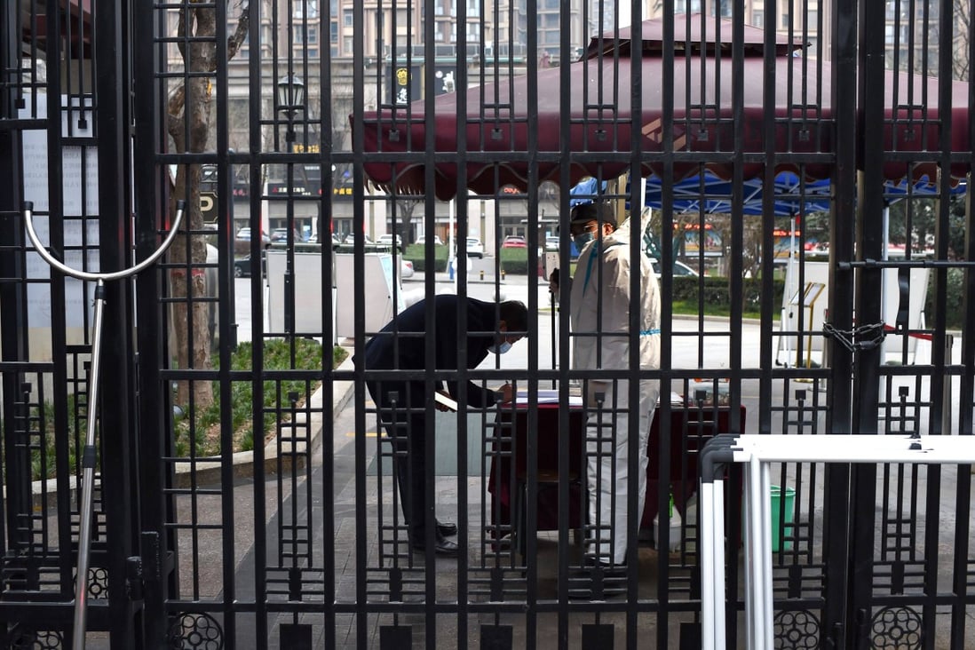 A security guard checks a resident’s information as they enter a residental area in Xian. Photo: AFP