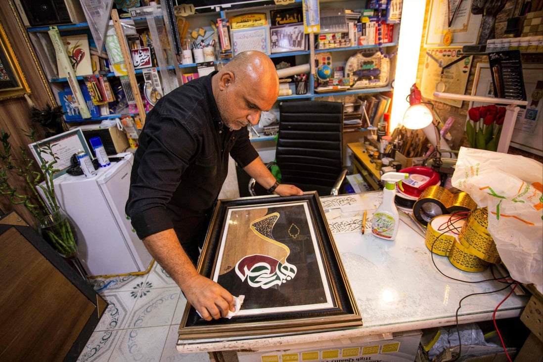 Iraqi calligrapher Wael al-Ramdan wipes the glass on one of his Arabic calligraphy framed art pieces at his workshop, in Basra, Iraq. A few dedicated artists are keeping the ancient tradition alive. Photo: AFP