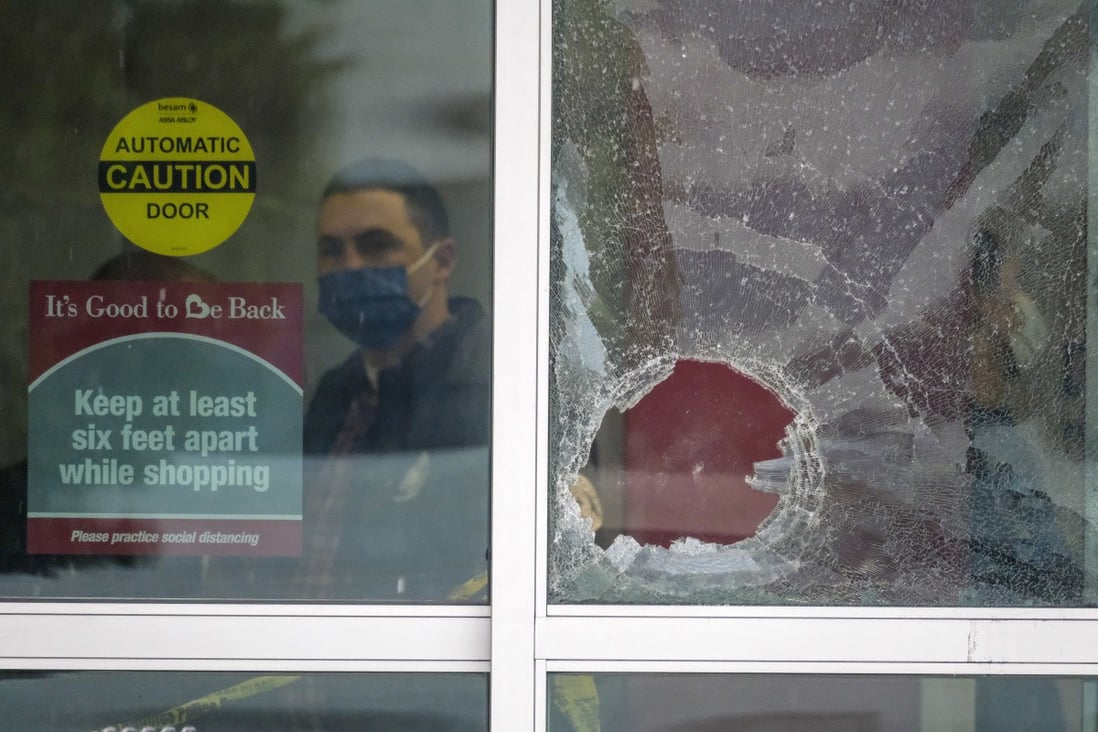 A police officer works behind a broken glass door at the scene where two people were struck by gunfire in California on Thursday. Photo: AP