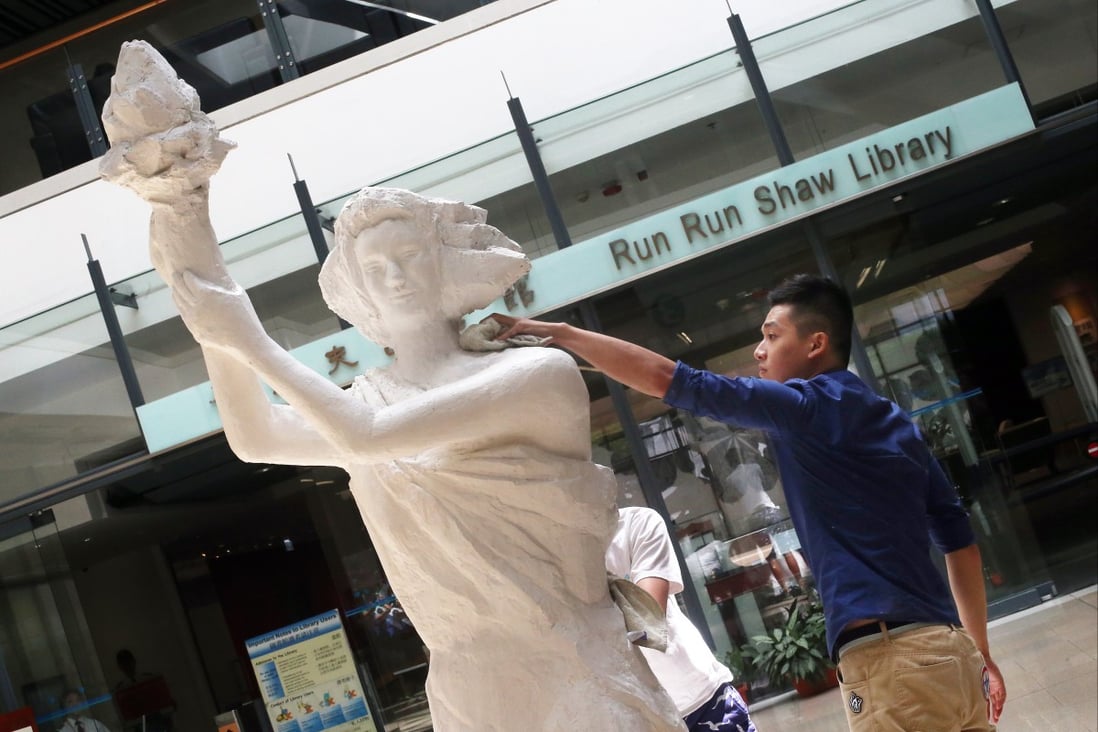 Students wipe the Goddess of Democracy statue on the City University campus. Photo: SCMP