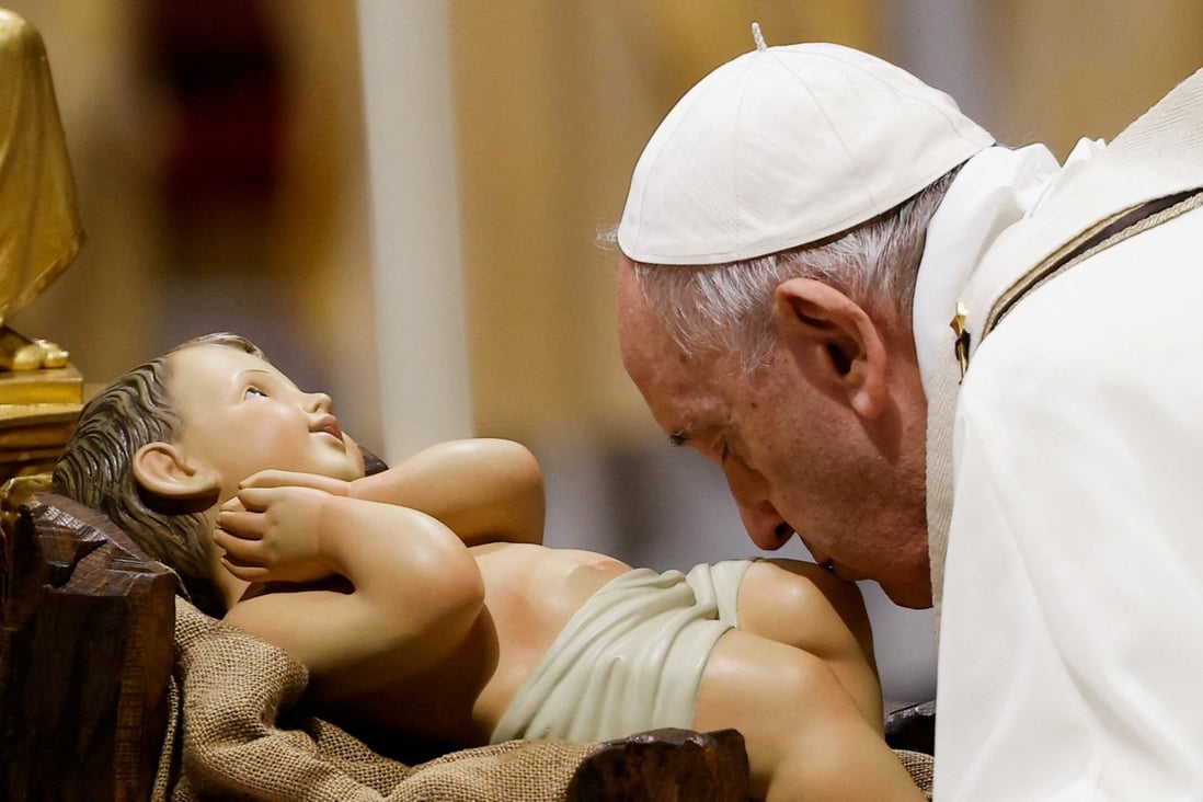 Pope Francis kisses a statue of baby Jesus as he celebrates Christmas Eve Holy Mass in St Peter’s Basilica on Friday. Photo: Reuters