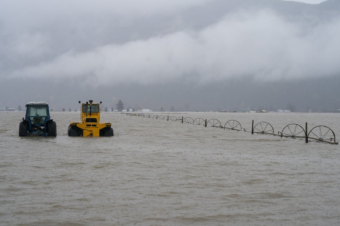 Tractors stand in a flooded field in British Columbia. Photo: AP