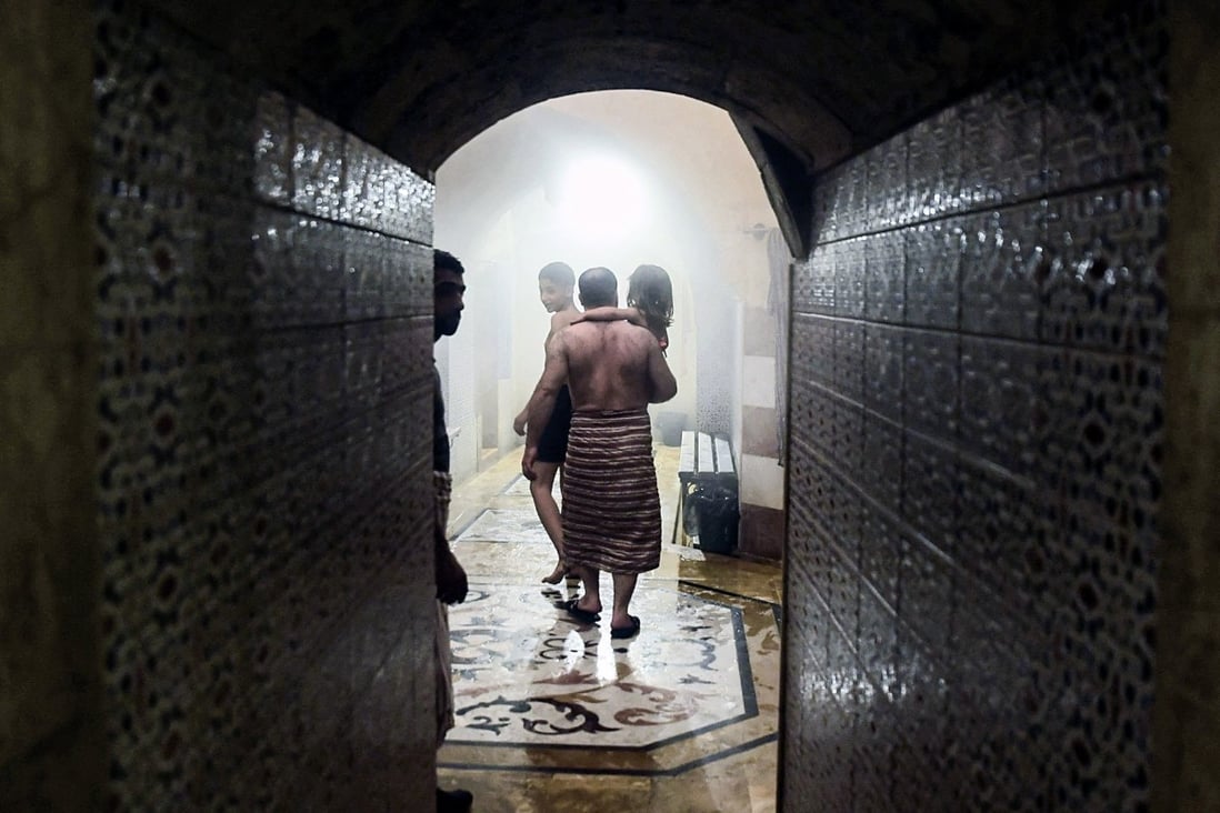 A man carries a child inside Hammam al-Qawas, a traditional Turkish bathhouse, in Syria’s northern city of Aleppo. Photo: AFP