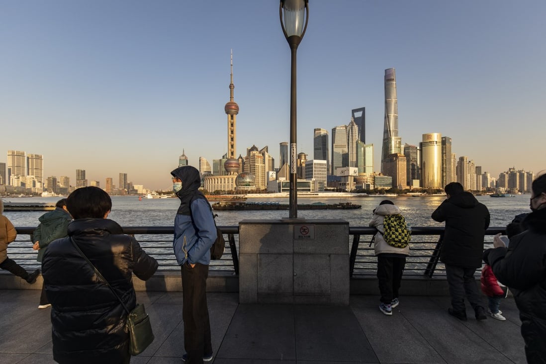 Pedestrians walk along the Bund in Shanghai on December 28 with the city’s financial district in the background. Photo: Bloomberg