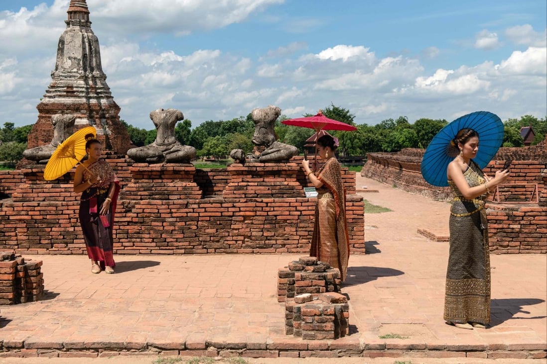 Visitors carrying sun umbrellas at the 17th century Wat Chaiwatthanaram temple complex in the ancient capital of Ayutthaya, north of Bangkok, Thailand. Photo: AFP