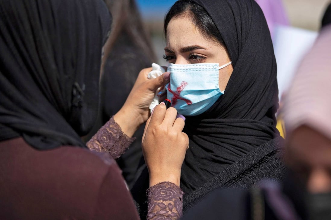 A demonstrator draws a cross on the mask of another protester as they attend a rally for International Women’s Day in Basra, Iraq, on March 8, 2021. Photo: AFP