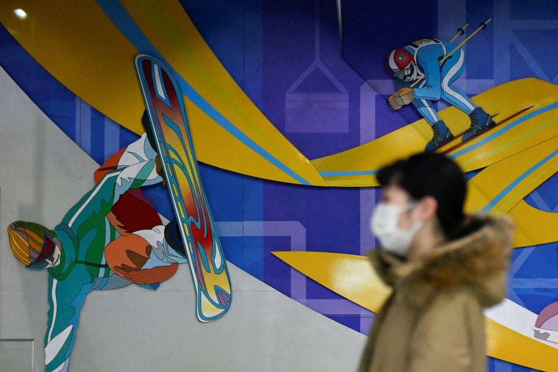 A woman walks past images of snow sports at a subway station in Beijing. Photo: AFP