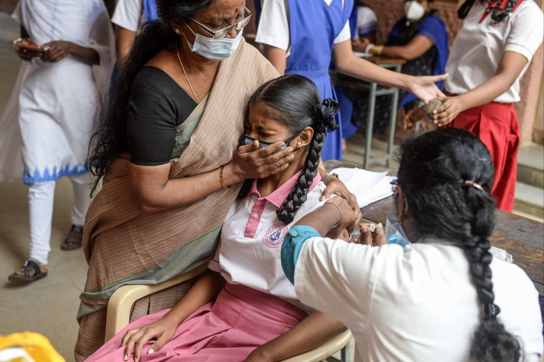 A teacher holds a student as she gets vaccinated against Covid-19 in Hyderabad, India. Photo: AFP