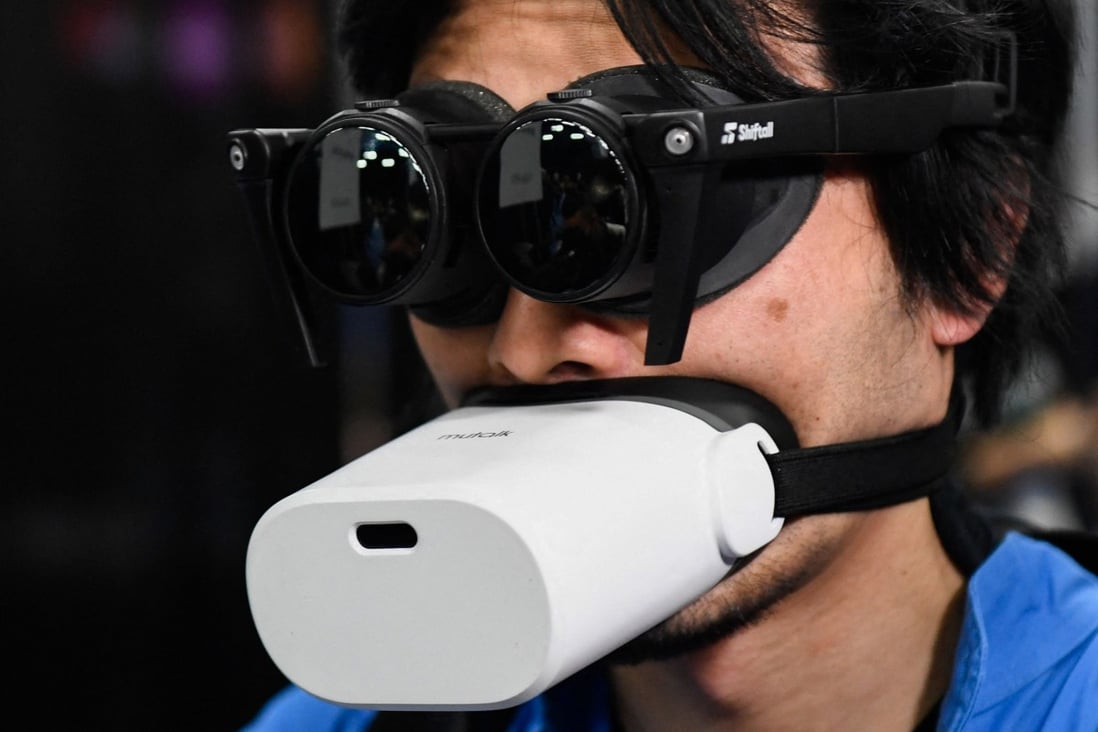 An attendee demonstrates a pair of virtual reality headphones and microphone for metaverse experiences ahead of the Consumer Electronics Show in Las Vegas, Nevada, on January 3, 2022. A number local governments in China have unveiled plans to support the development of the metaverse. Photo: AFP

