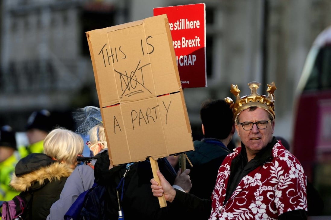 Protestors hold placards in Parliament Square as Britain’s Prime Minister Boris Johnson attends the weekly Prime Ministers’ Questions session in parliament in London on January 12. Johnson has apologised for attending a garden party during Britain’s coronavirus lockdown, but brushed aside opposition demands that he resign. Photo: AP
