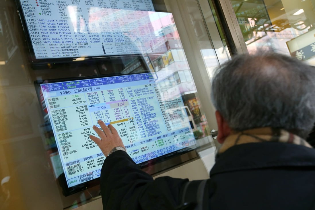 People pointing at an electronic board showing stock prices in Mong Kok, Hong Kong. Photo: David Wong