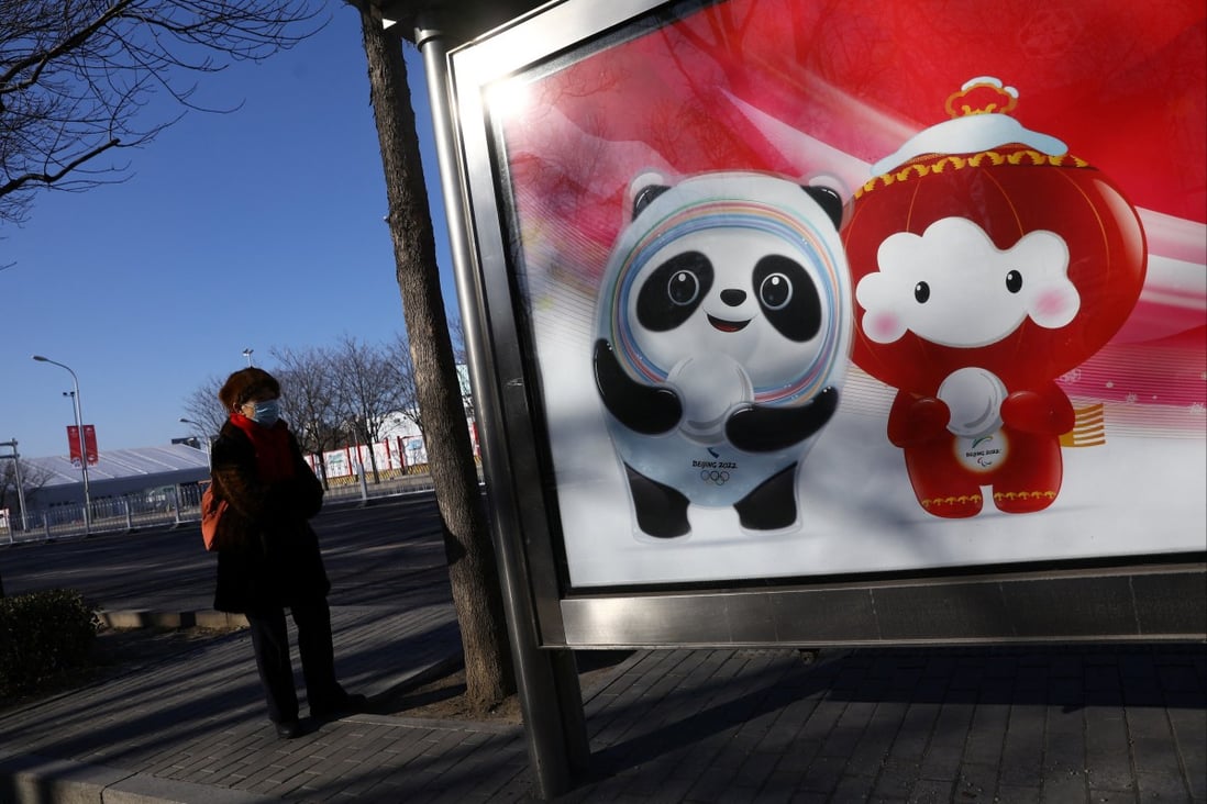 A woman stands near a board with an image of the Beijing Winter Olympics mascots, at a bus stop near the Winter Olympic Village, on January 27. Photo: Reuters