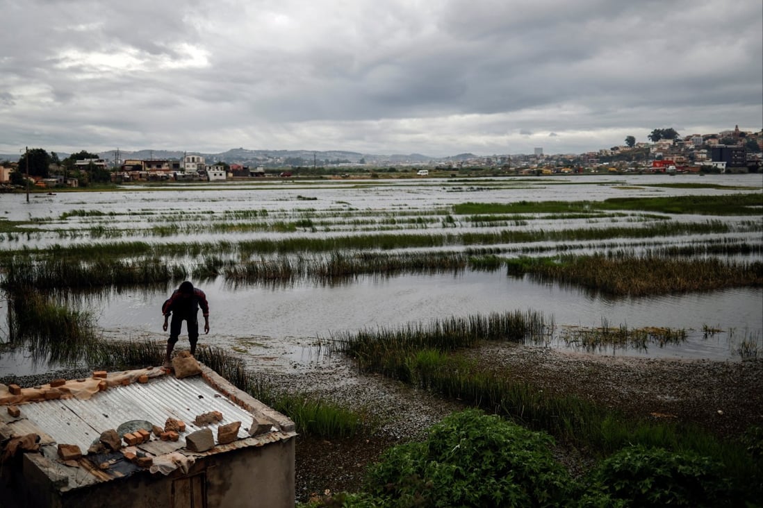 A man reinforces the roof of a house with stones and sacks of sand a day before Cyclone Batsirai is expected to hit Madagascar. Photo: Reuters