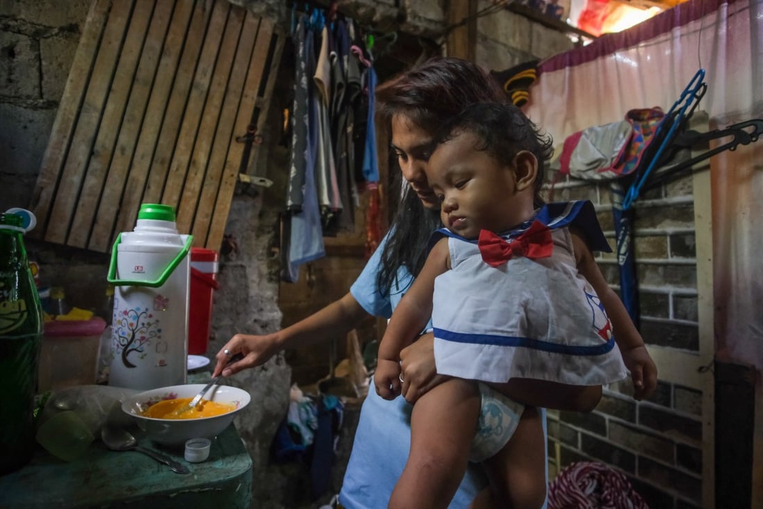 Erlyn, 18, prepares food while holding her baby son. The youngster quit school at 17 after her brother’s sudden death and began working as a masseuse. She then met the man who became her husband and fell pregnant. Photo: Geela Garcia