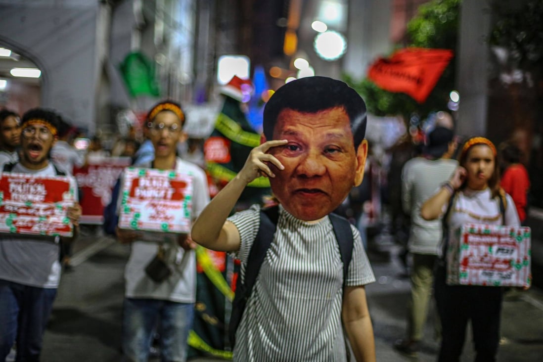 A human rights advocate holds up a mask featuring the image of Philippine President Rodrigo Duterte during a protest in Manila. Photo: AFP