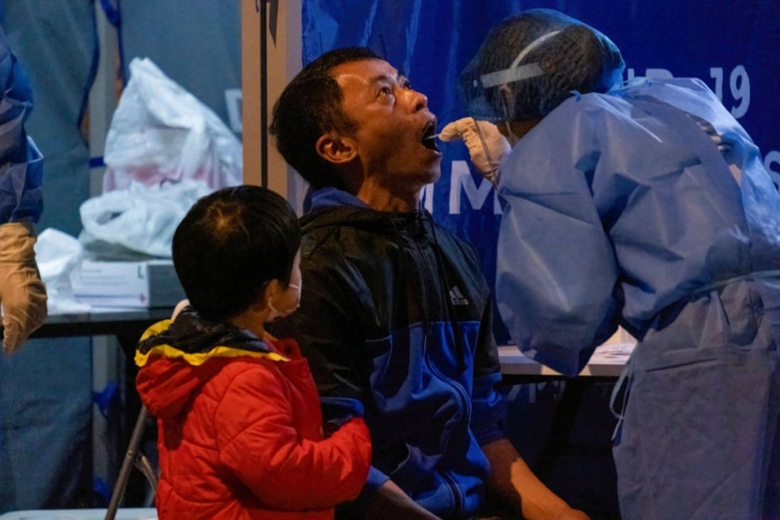 A medical worker wearing collects swab samples from a man during mandatory coronavirus testing in Hong Kong as a boy looks on. Government rules that change frequently are causing families stress. Photo: Isaac Wong/SOPA Images/LightRocket via Getty Images