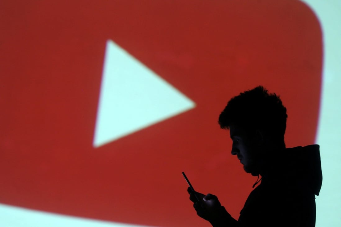 Silhouette of mobile user is seen next to a screen projection of the YouTube logo in this picture illustration taken March 28, 2018. Photo: Reuters