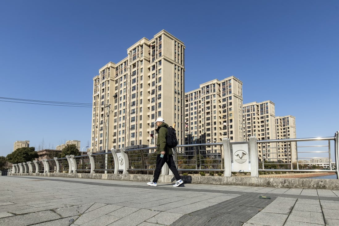 A pedestrian passes near residential buildings at a Zhenro Properties Group development in the Jinshan district of Shanghai on February 24. Zhenro is asking bondholders for more time to pay back about US$1 billion in debt due to mature this year, citing liquidity pressure. Photo: Bloomberg
