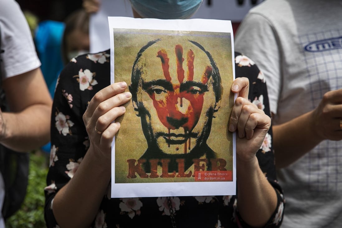 A Ukrainian protester holds up a poster of Russian President Vladimir Putin with the word “killer” during a rally outside the Russian embassy in Bangkok, Thailand in February. Photo: TNS