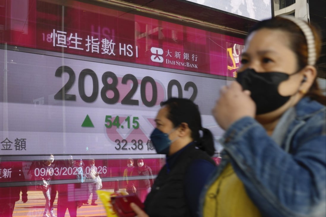 People walk past a bank’s electronic board showing the Hang Seng Index on March 9, 2022. Photo: AP