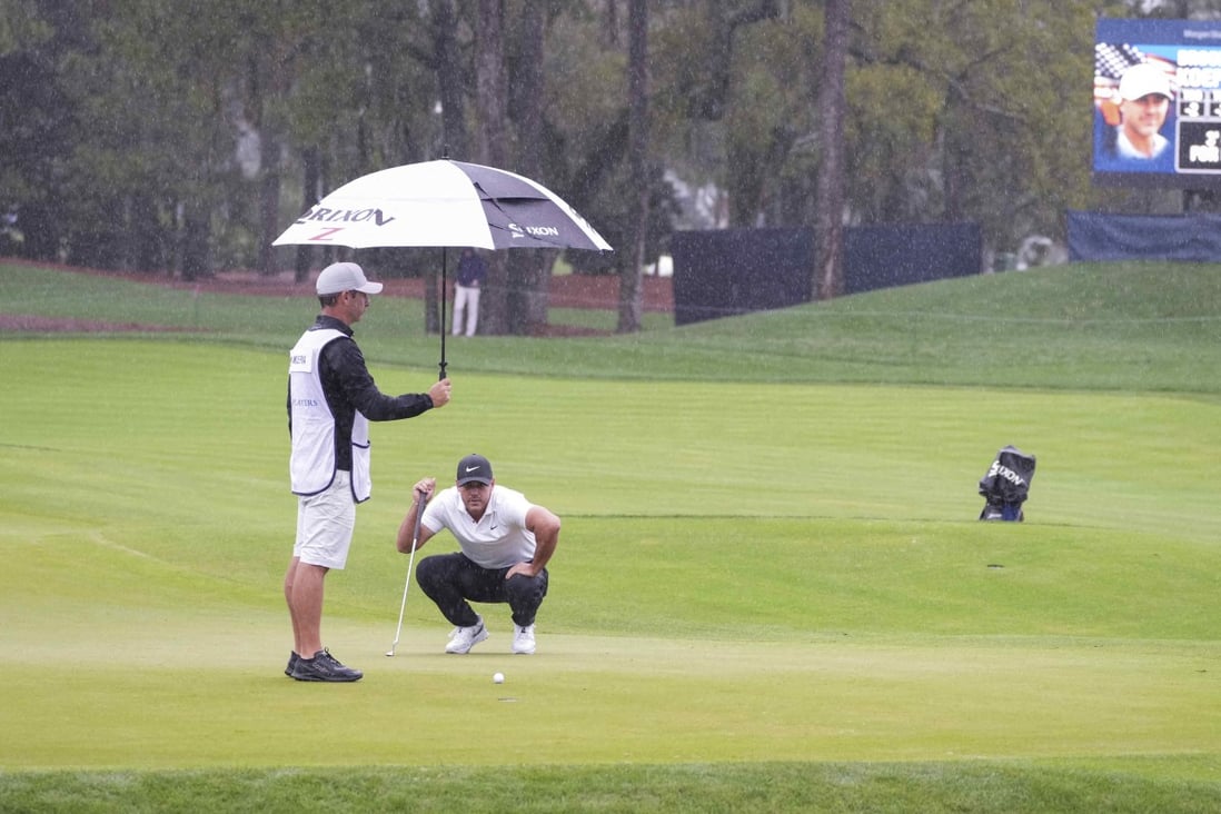 Caddie Ricky Elliott keeps the rain off Brooks Koepka as he studies a putt on the 11th green during the first round of The Players Championship. Photo: USA Today Sports