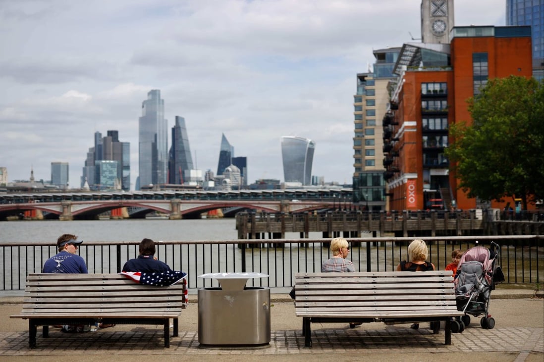 People sit in the sunshine beside the River Thames in London on July 3, 2020. Photo: AFP
