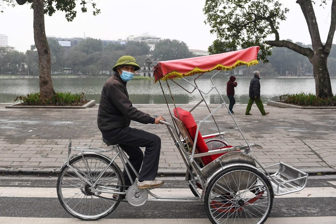 A driver looks for customers along Hoan Kiem Lake in downtown Hanoi. Photo: AFP 