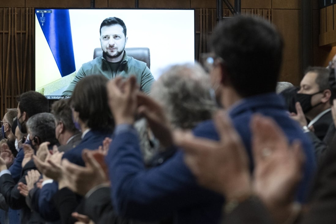 Canadian lawmakers applaud as Ukrainian President Volodymyr Zelensky is shown on a video screen before addressing the House of Commons on Tuesday. Photo: The Canadian Press via AP
