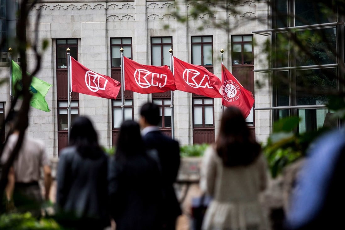 People walk before flags of CK Hutchinson Holdings outside the company’s headquarters in Hong Kong on March 21, 2019.Photo: AFP