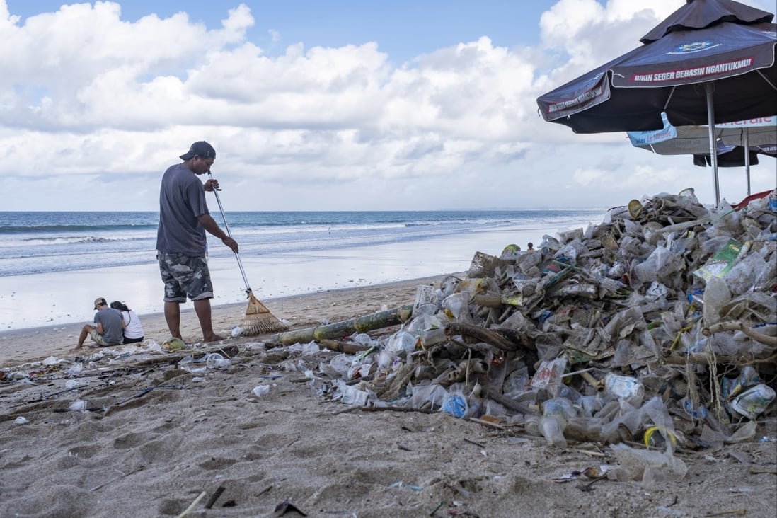 A worker cleans up piles of debris and plastic waste brought in by strong waves at Kuta Beach in Bali, Indonesia, on December 10, 2021.  Photo: EPA-EFE