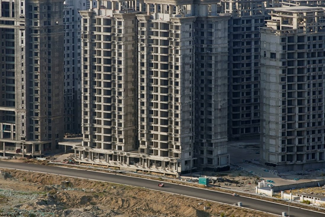 A vehicle travels past some of the 39 buildings developed by China Evergrande Group for which authorities have issued demolition orders in Danzhou, Hainan province, on January 6. Beijing has pledged to ease pressure on the stricken residential property sector by reducing risks faced by developers, but concerns remain that the move is too little, too late. Photo: Reuters