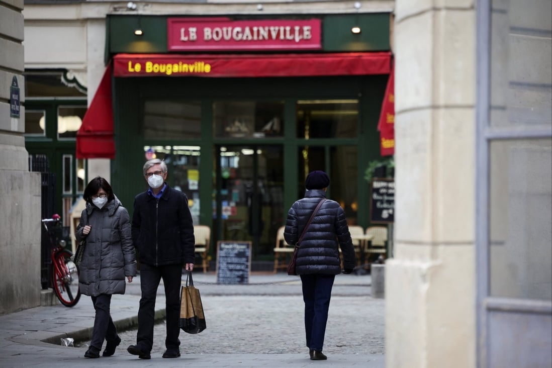 People wear protective face masks as they walk along a street in Paris, France. Photo: Reuters