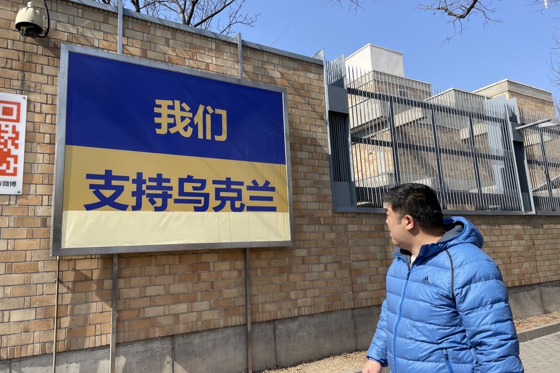 A man looks at a billboard which reads: ‘We are together with Ukraine’; outside the Canadian Embassy in Beijing, China. Photo: Simon Song