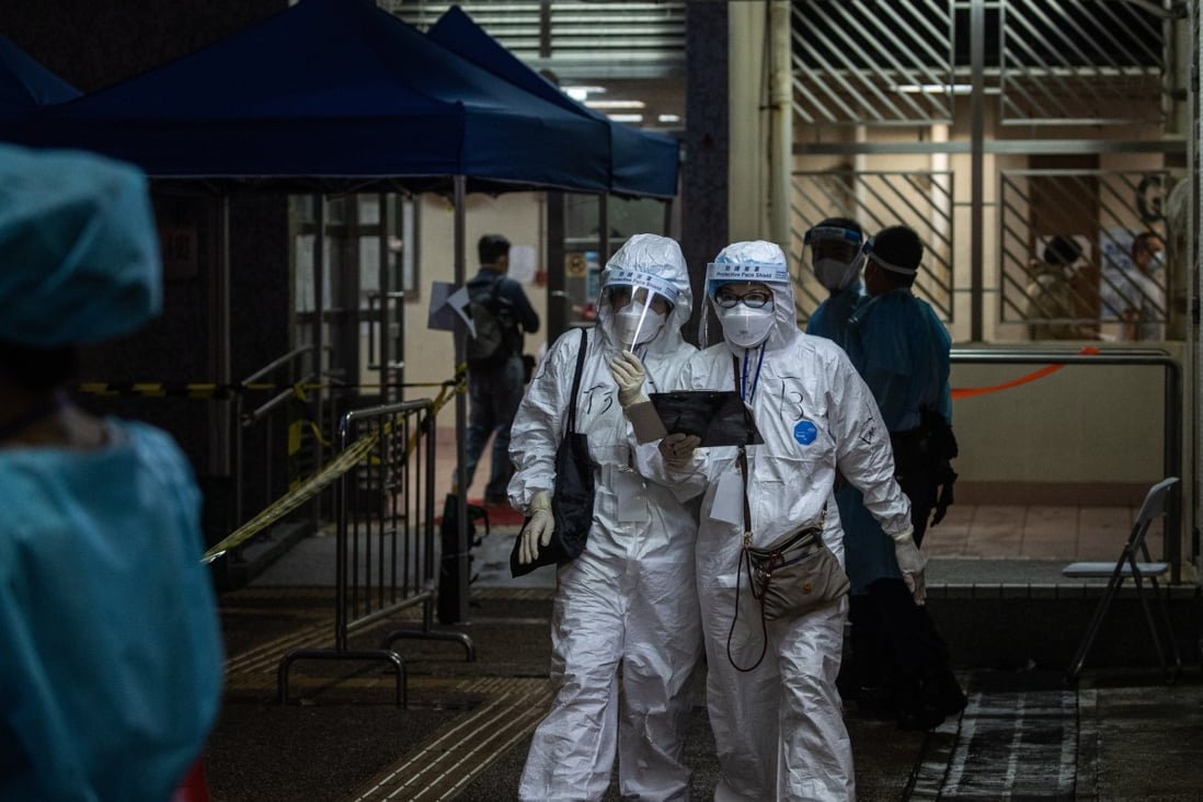 Health workers walk out of a building under lockdown in Hong Kong on March 25. Photo: EPA