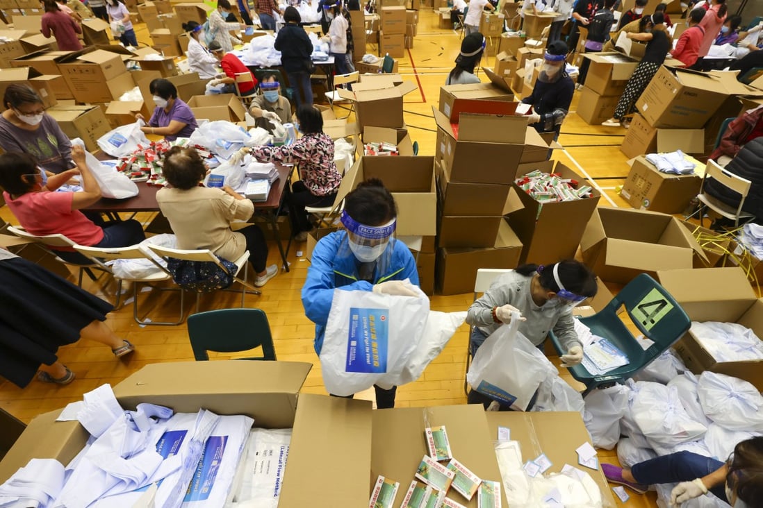 Volunteers pack kits of rapid Covid-19 tests, masks and medicine set to be distributed to Hong Kong residents at Tai Wo Hau Sports Centre.  Photo: Dickson Lee