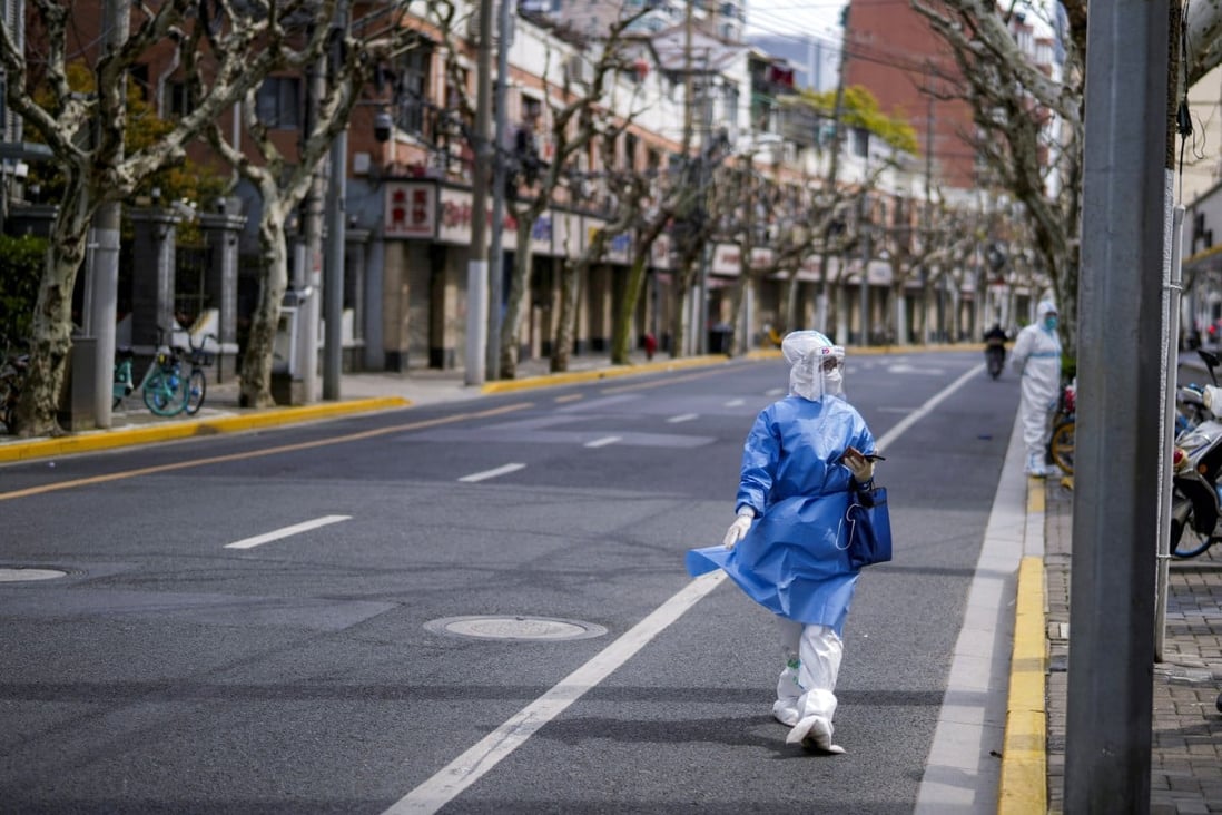 A worker in a protective suit keeps watch on a street, as the second stage of a two-stage lockdown began in Shangha. Photo: Reuters