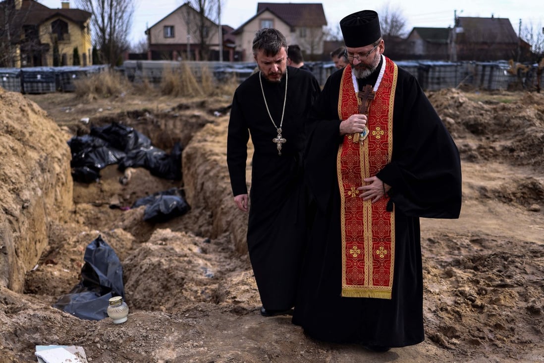Priests pray over body bags in a mass grave in the garden surrounding the St Andrew church in Bucha, Ukraine, on April 7. Photo: TNS