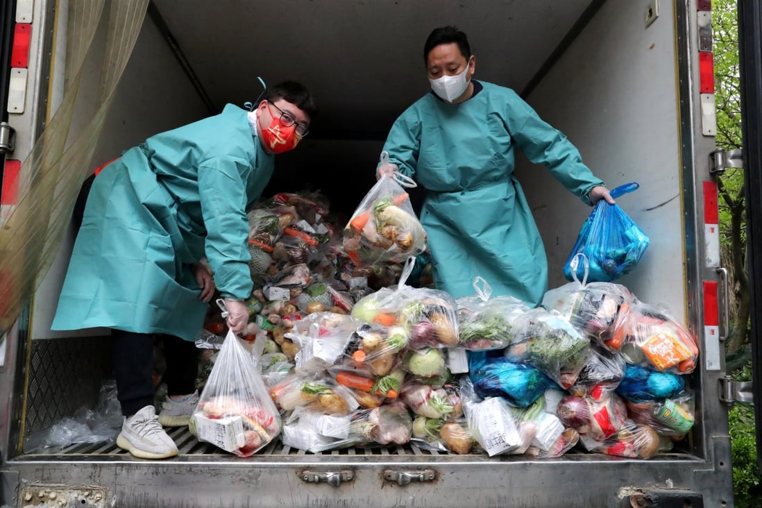 Workers wearing protective gear sort bags of vegetables and groceries on a truck to distribute them to residents at a residential compound, during the lockdown to curb the coronavirus disease (COVID-19) outbreak in Shanghai on April 5, 2022. Photo: China Daily via Reuters