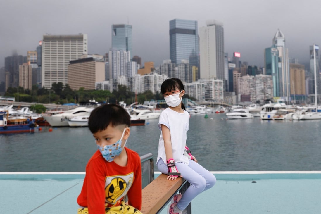 Children wearing face masks rest next to Victoria Harbour on March 25. Photo: Reuters