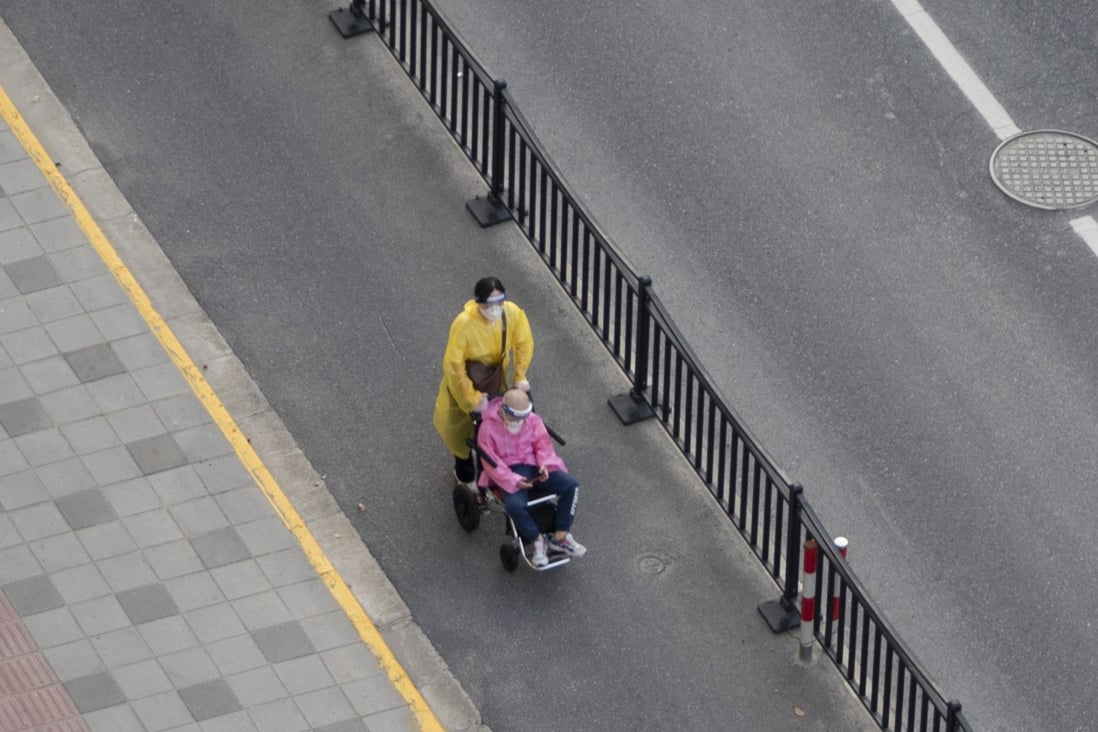 A pedestrian pushes an elderly man in a wheelchair on a street in Shanghai, China, On April 12. Photo: Getty