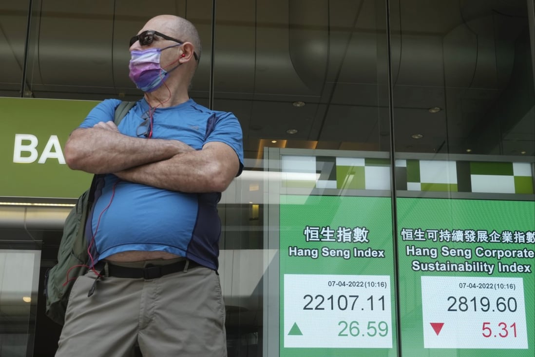 A man stands next to a bank’s electronic board showing the Hong Kong share index. Photo: AP Photo
