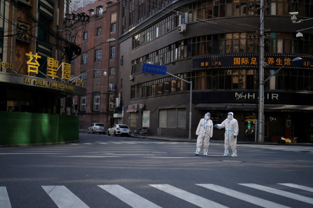 Workers in protective suits keep watch on a deserted street during a lockdown in Shanghai on April 16. Photo: Reuters
