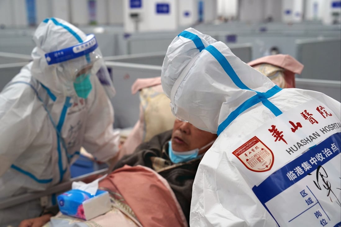 Medical workers talk with a patient in a makeshift hospital in Shanghai in eastern China on Saturday. The makeshift hospital in Lingang is converting around 2,000 beds to treat Covid-19 patients with moderate symptoms and patients over 80 years old. Photo: Xinhua