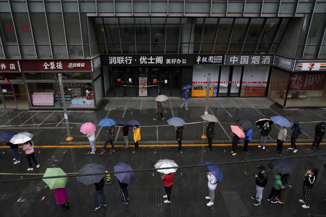 Locked-down residents line up in the rain for Covid-19 testing outside a closed office complex in Beijing. Photo: AP