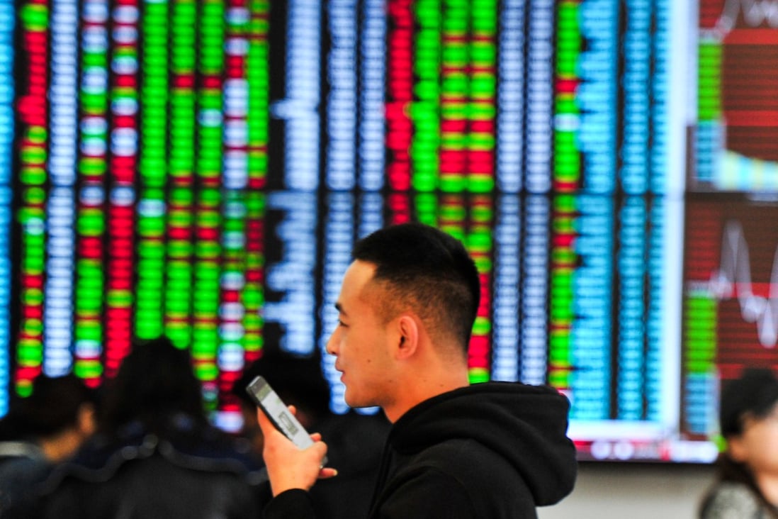 A man talks on his mobile phone with big screen showing stock prices behind at a stock brokerage house in Shenyang. Photo:: China Photo Press