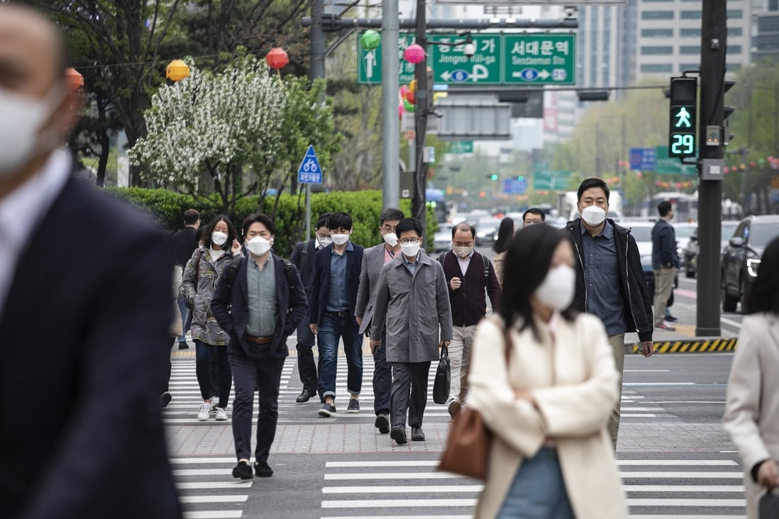 Morning commuters wearing face masks cross a road in Seoul earlier this month. Photo: Bloomberg